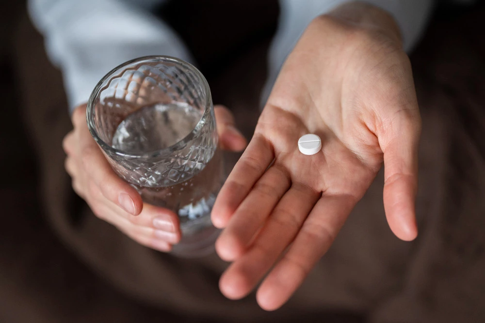 close-up hands holding pill glass