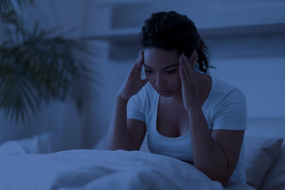 sleepless black woman sitting in bed alone at night