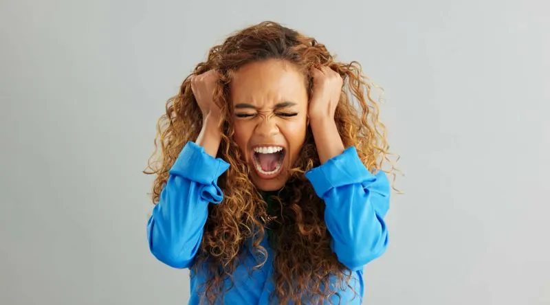 Woman screaming and pulling her hair, experiencing a panic attack.